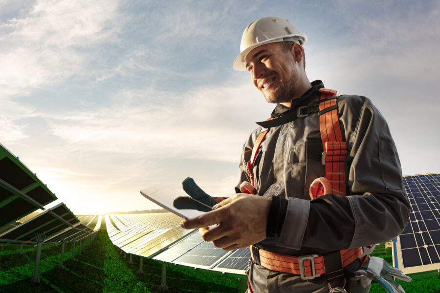 Employee in hardhat standing by solar panels.